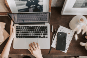 Overhead view of a restaurant owner using a laptop and smartphone to manage digital citations and AI search visibility.