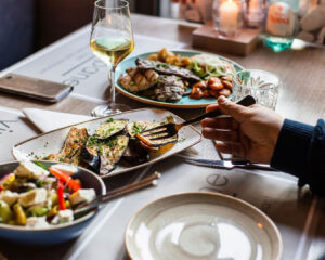 A person smiling while enjoying a plated meal at a cosy restaurant table, with warm lighting and a relaxed dining atmosphere.