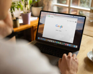 A man opening a laptop and viewing Google search results related to restaurant services and online visibility.