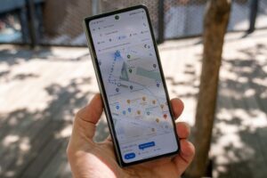 A person's hand holds a tall, narrow smartphone displaying Google Maps with walking directions to Chelsea Market.
