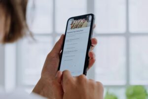 A person holds a smartphone while navigating a food delivery app to order a "Supreme Taco Party Pack."