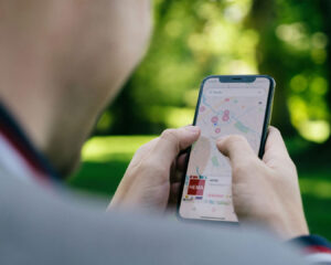A man’s hand holding a smartphone while placing a location pin on Google Maps, indicating he is manually marking or searching for a specific destination.