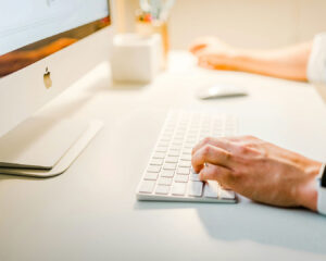 A close-up view of hands typing on a laptop keyboard, representing digital work or communication.