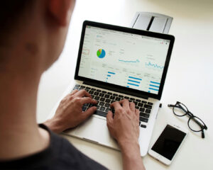 A man working on a laptop displaying SEO performance graphs and analytics, suggesting digital marketing or business strategy planning.