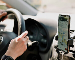A smartphone mounted inside a car showing Google Maps navigation on the screen, guiding the driver along a route while travelling.