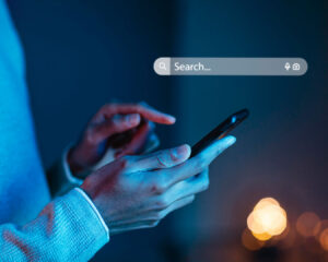 Hand holding a smartphone in search position, indicating the user is about to look up a restaurant or food place.