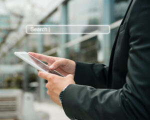 A hand holding a smartphone as a search bar pops up on the screen, illustrating mobile browsing and quick access to online searches anytime, anywhere.