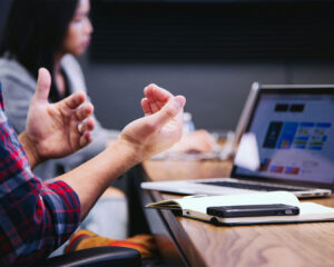 A small team gathered around a table with laptops, engaged in a discussion or collaborative meeting