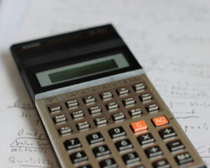 Calculator placed on a desk with financial documents, symbolising budgeting, cost calculation, and business planning.