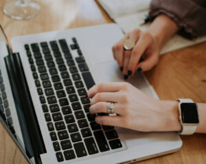 A close-up of hands typing on a laptop keyboard, representing digital marketing work and website content creation.