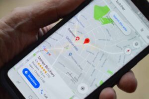 A hand holds a smartphone displaying a Google Maps profile for a business called Morley Butchers in the Crouch End neighborhood.