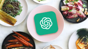 This image features a top-down view of several gourmet dishes, including salads and roasted vegetables, arranged on a white marble surface. Centered in the composition is a pink plate holding a green square icon with a white, circular geometric logo.