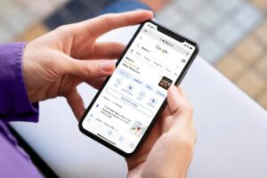 A person is holding a smartphone that displays a Google search result for an Italian restaurant called "Bistro V." The screen shows restaurant details like a 4.2-star rating, a location in Tokyo, and options to make a reservation.