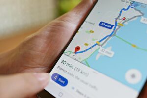 A person holds a smartphone showing a Google Maps navigation route in Malaysia that estimated to take 30 minutes for a 19 km trip.