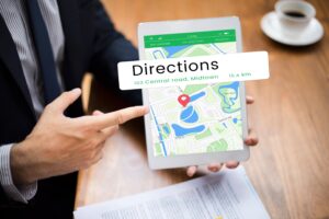 A person in a business suit points toward a tablet displaying a navigation app with a map and a location pin. A large "Directions" graphic overlays the screen, indicating a destination on Central Road in Midtown.