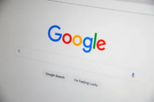 Google search homepage with a colorful logo, a search bar below, and buttons labeled "Google Search" and "I'm Feeling Lucky" on a clean white background.